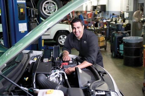 Mechanic standing in front of car with hood up